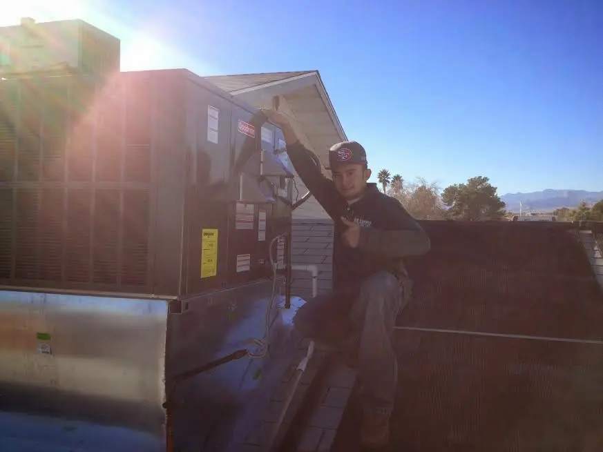 HVAC technician performing Heat Pump Repair on a rooftop unit in Bloomington